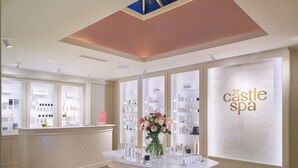 A spa interior with a reception desk, a vase of flowers, and shelves of spa products.