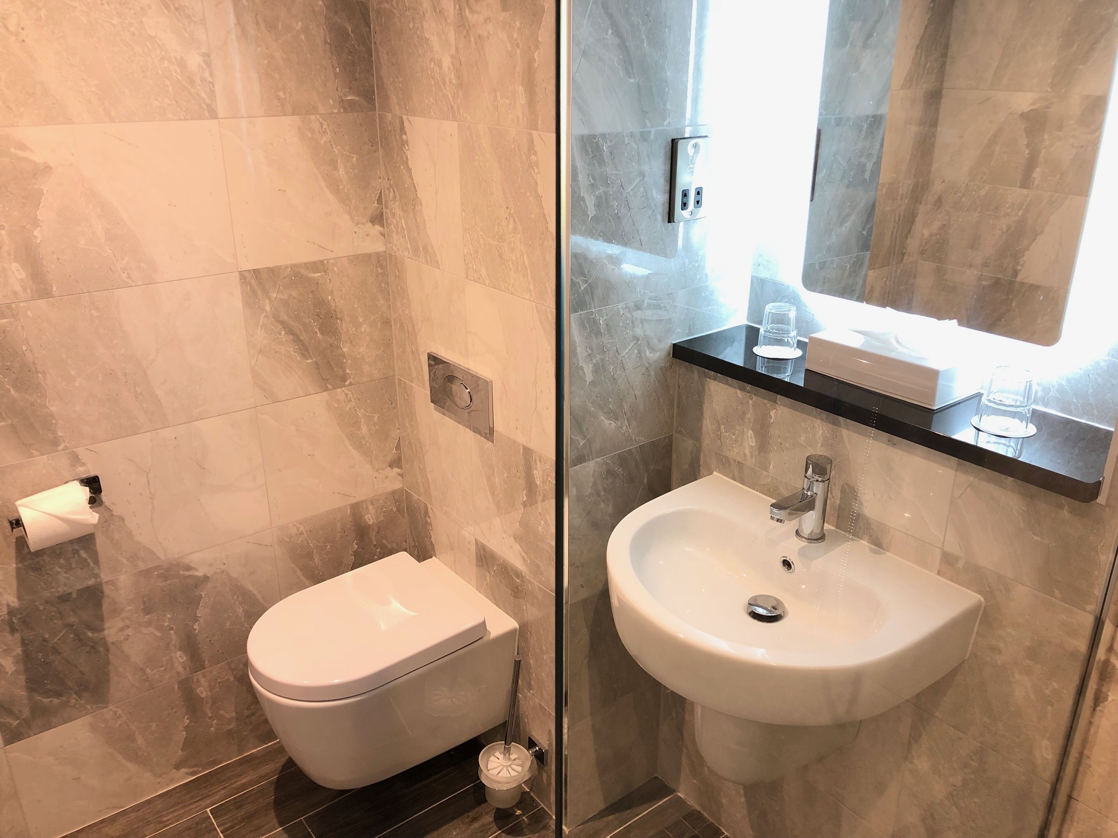 A modern bathroom with a toilet, sink, and a glass shower enclosure.