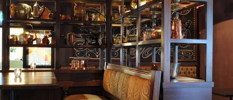 A cozy seating area with a wooden bench and a high shelf filled with various kitchenware.