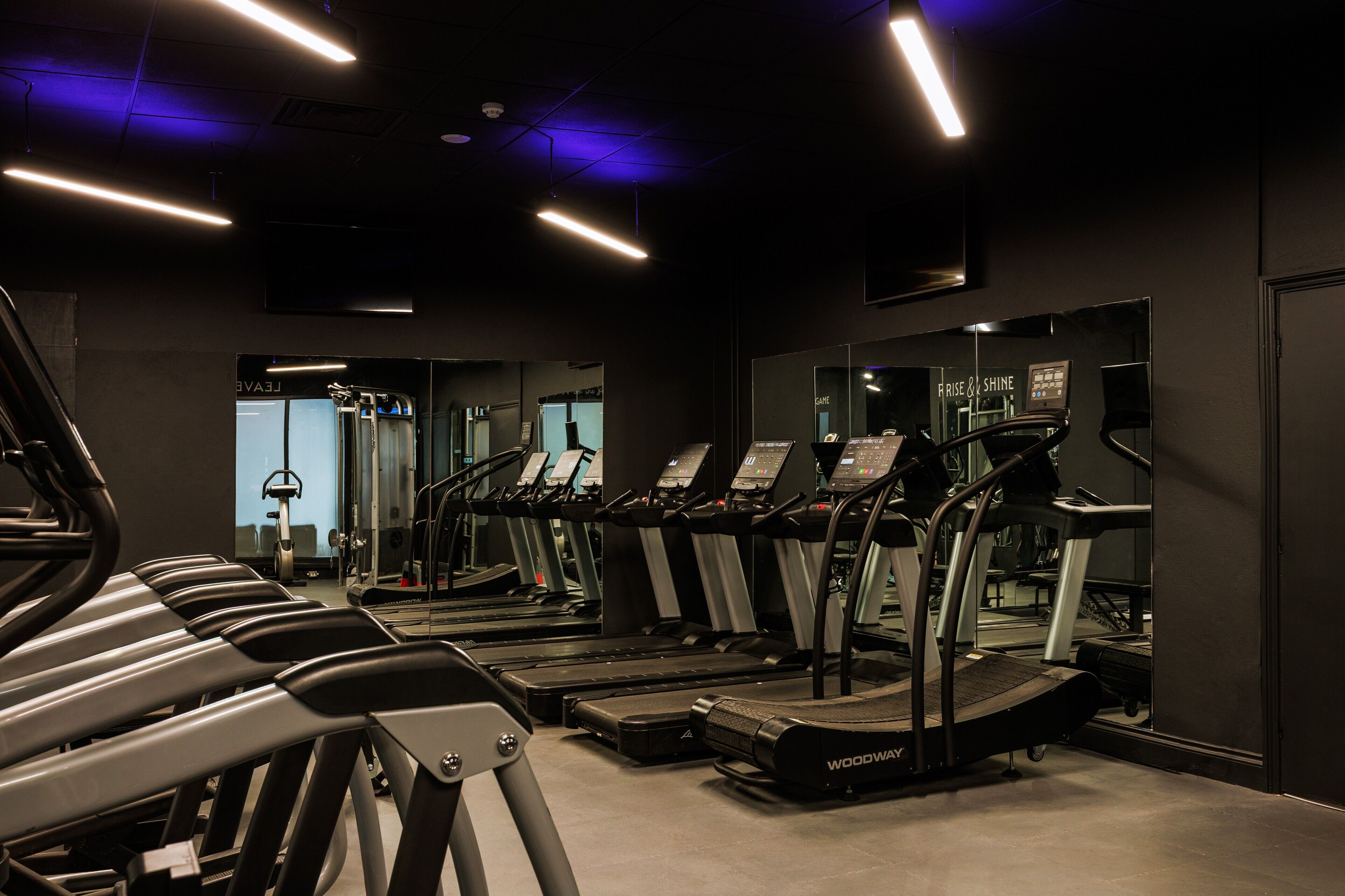 A gym with multiple treadmills, exercise bikes, and weight machines.