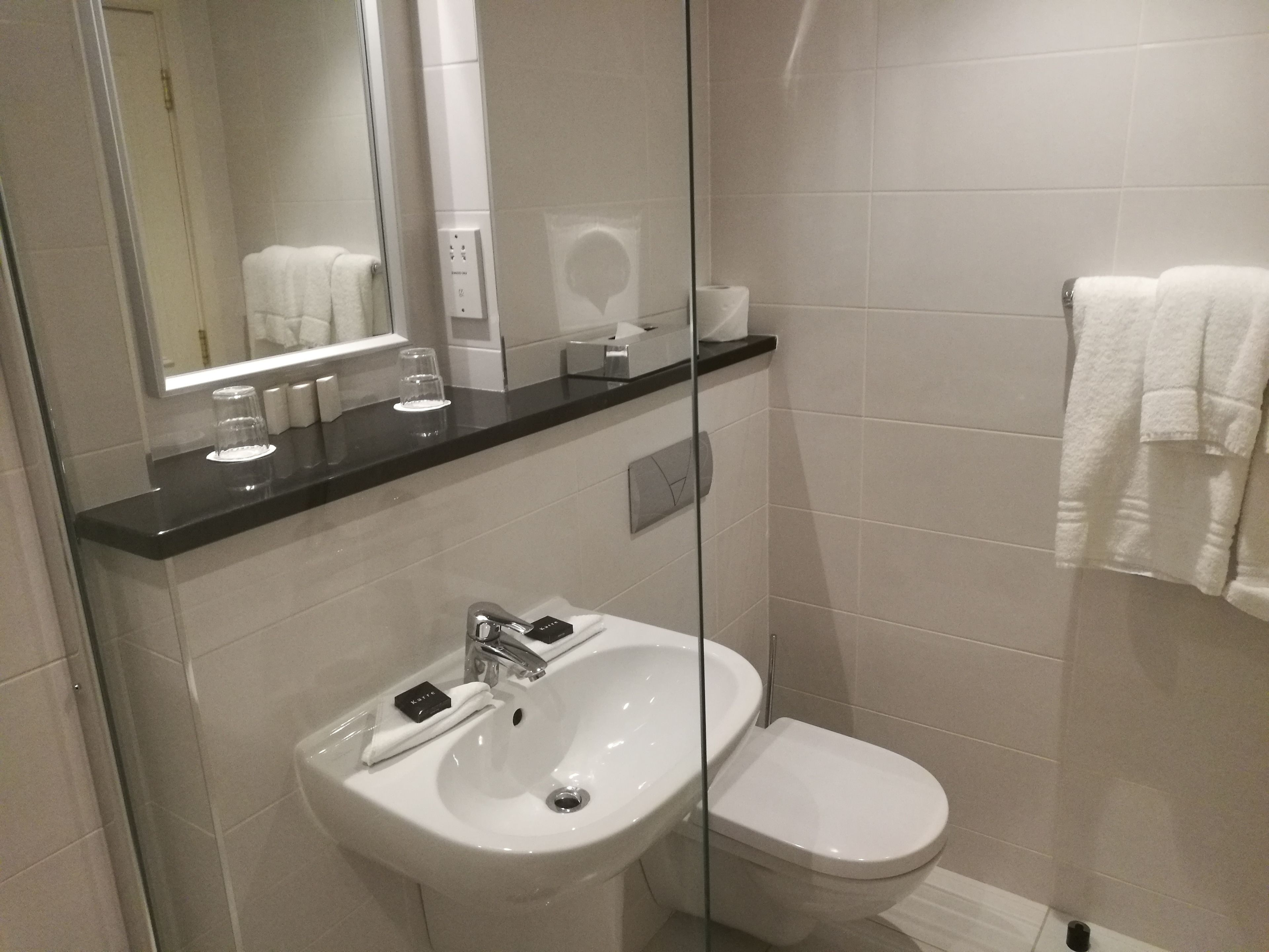 A modern bathroom with a white sink, toilet, and glass shower enclosure.