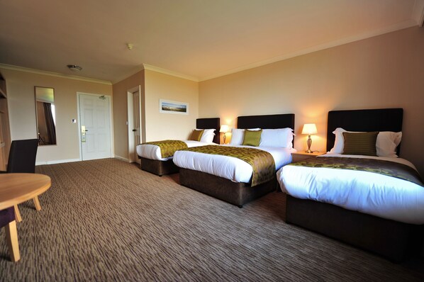 A hotel room with two beds, a desk, and a chair.