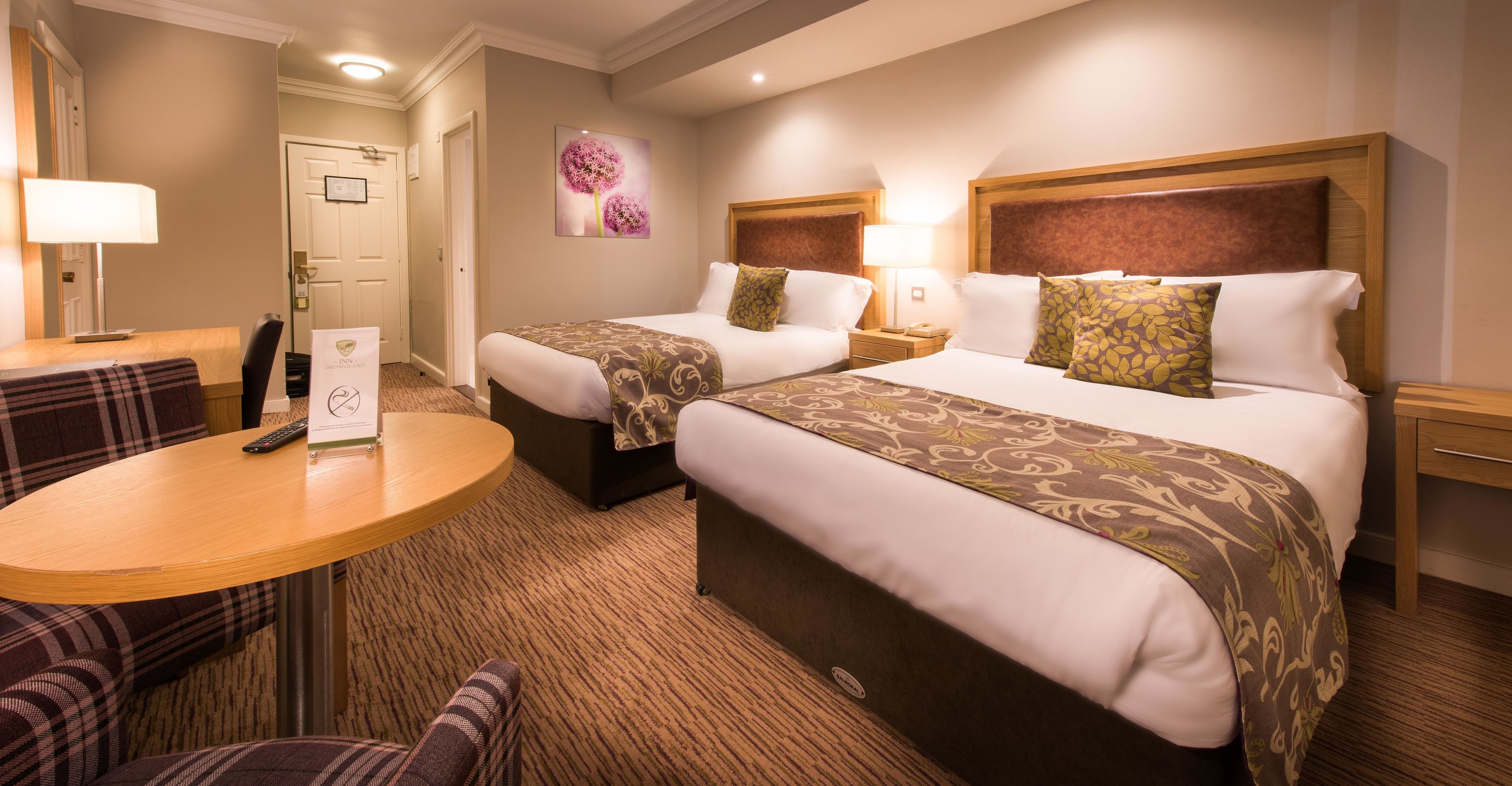 A hotel room with two beds, a round table, and a chair.