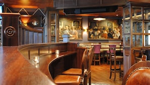A bar area with wooden furniture, a checkered floor, and a mural depicting a historical scene.