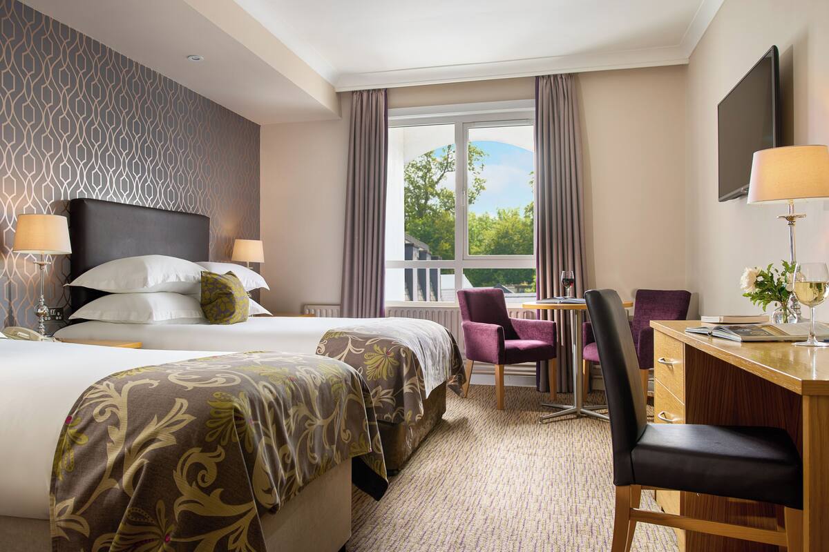 Une chambre d’hôtel avec deux lits, un bureau et une chaise.
