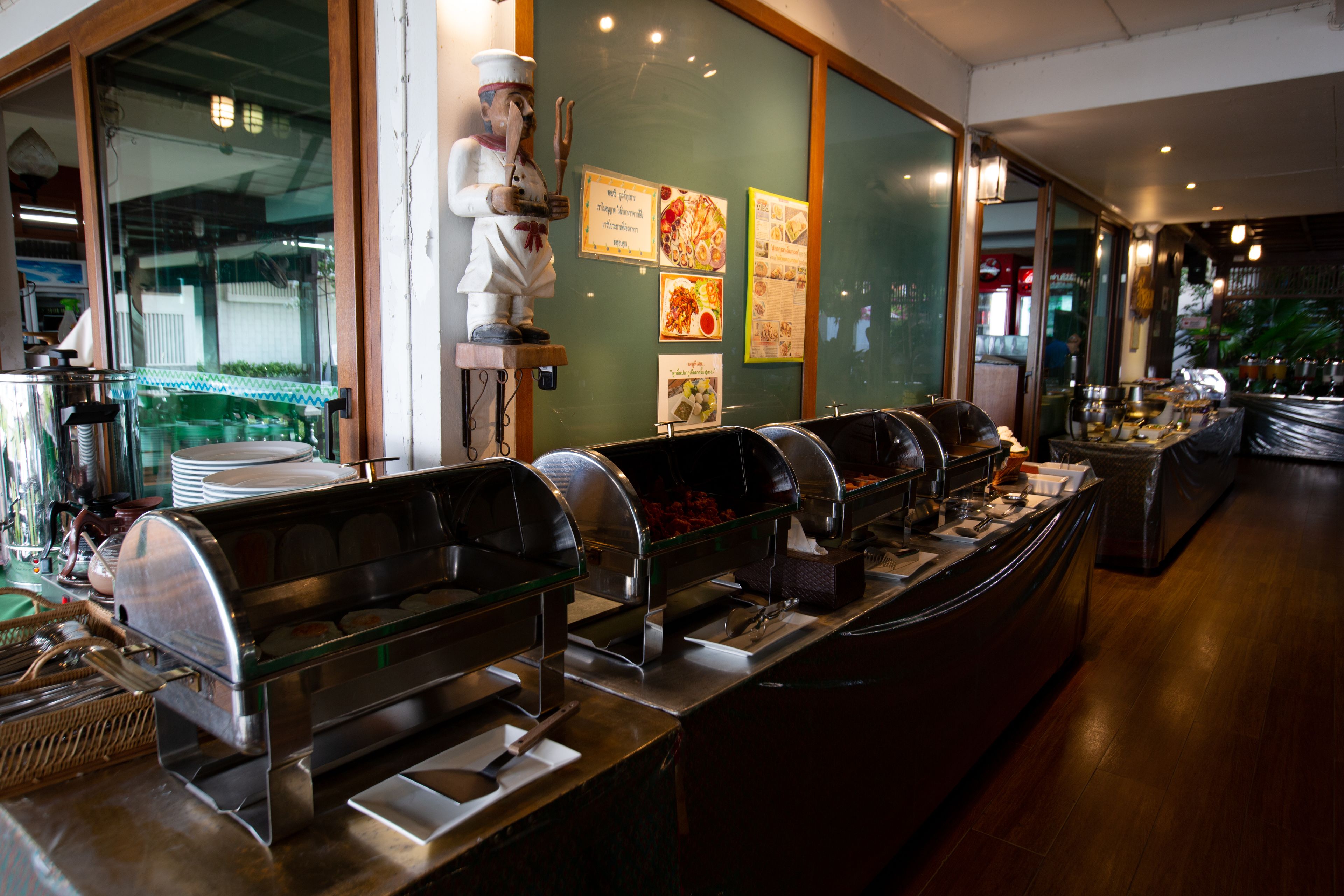 A buffet area with multiple food stations, a chef statue, and a menu board on the wall.