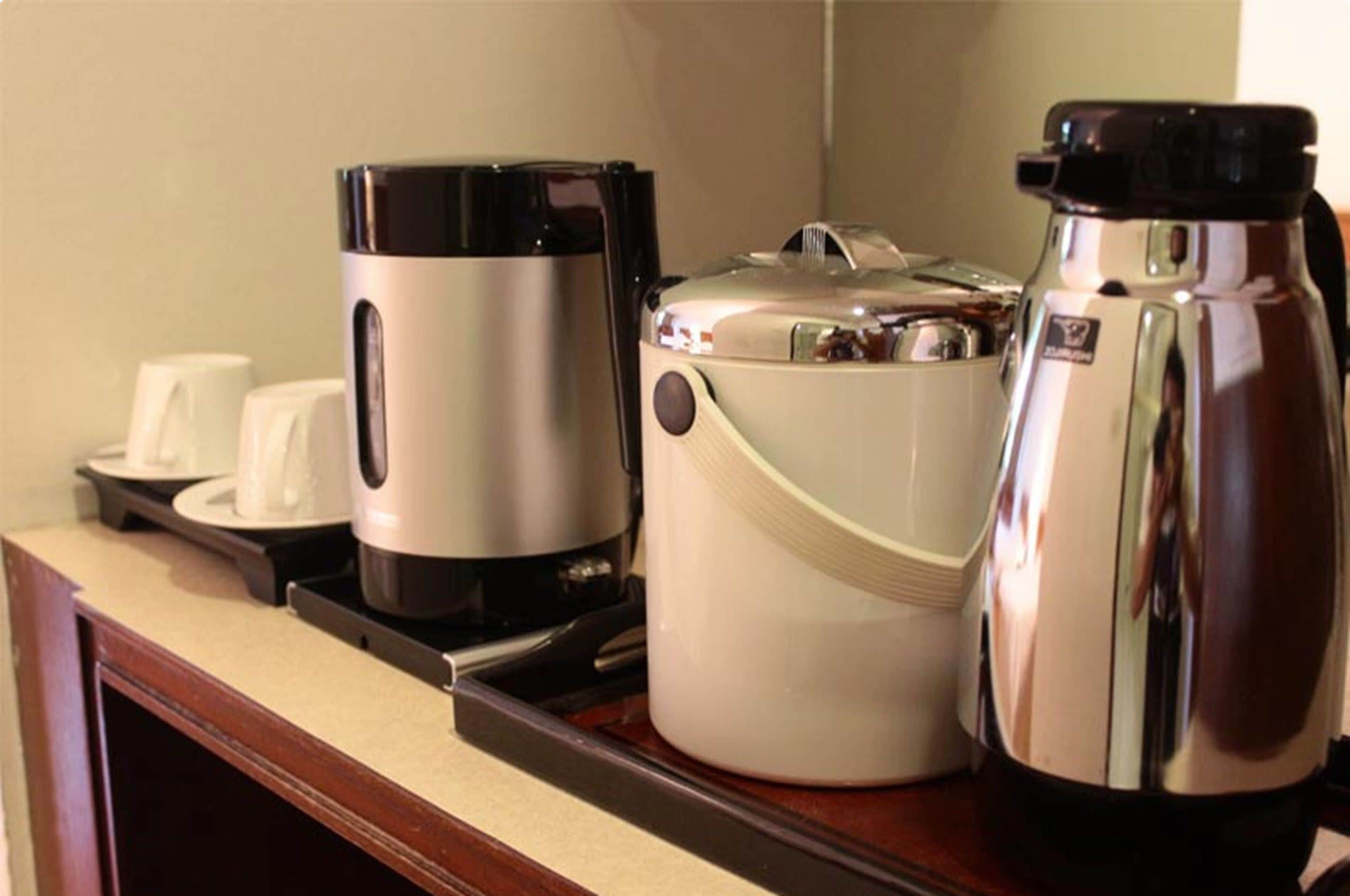 Una encimera de cocina con una cafetera, un hervidor y una tetera.