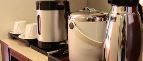 Una encimera de cocina con una cafetera, un hervidor y una tetera.