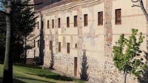 Un edificio histórico con una torre, muros de piedra y un patio.