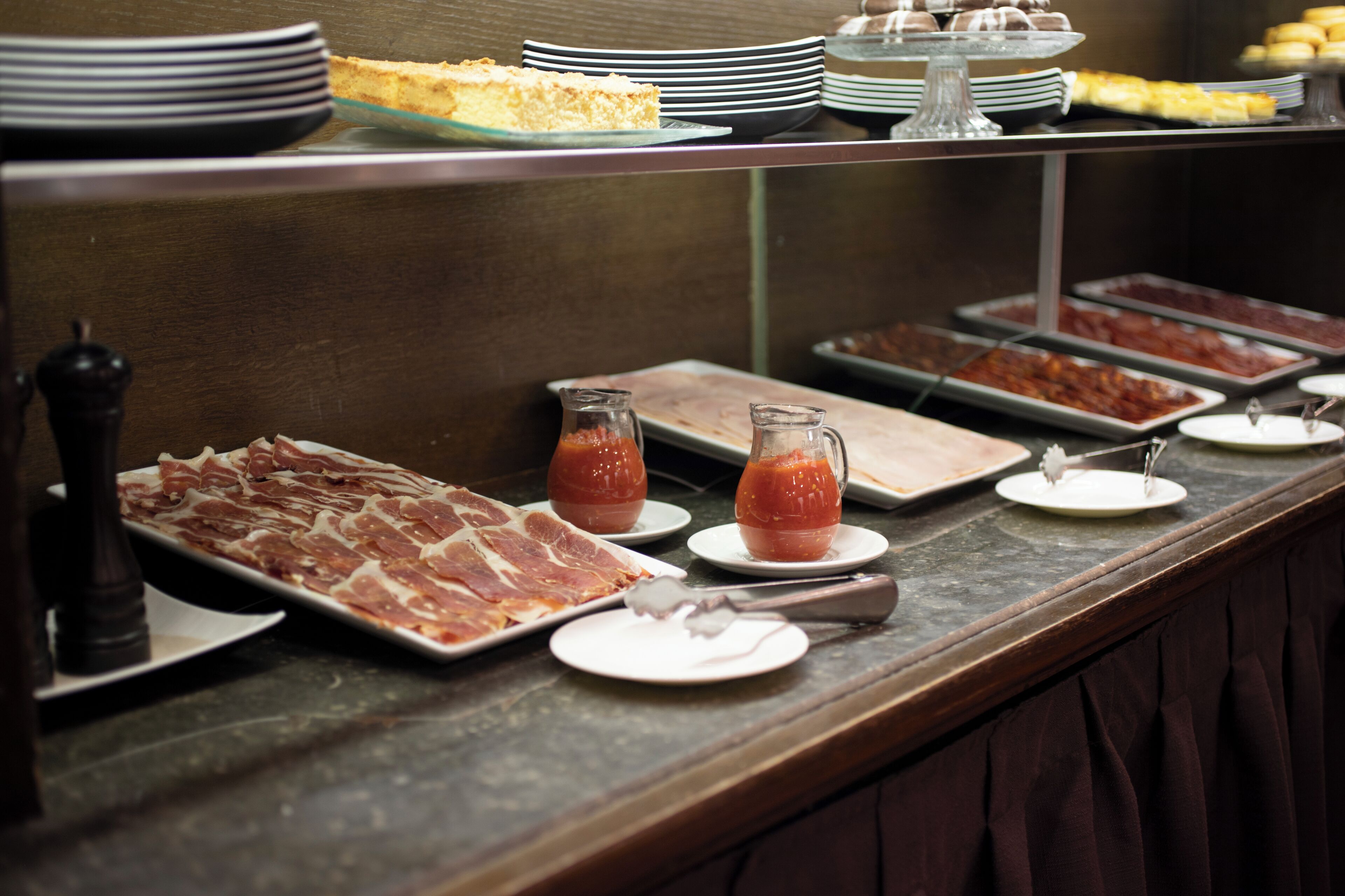 A buffet with various food items including meats, cheeses, and condiments.