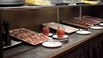 A buffet with various food items including meats, cheeses, and condiments.