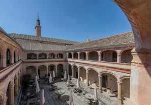 Un patio con varios niveles de arcos, zonas de estar al aire libre y la cúpula de una iglesia a la vista.