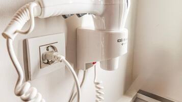 A hairdryer mounted on a wall with a coiled cord.