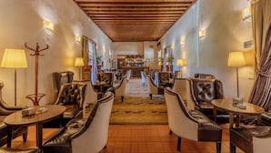 Un vestíbulo de hotel con sillones de cuero, una zona de bar y suelo alfombrado.