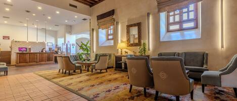 A lobby with a reception desk, seating area, and a large window with curtains.