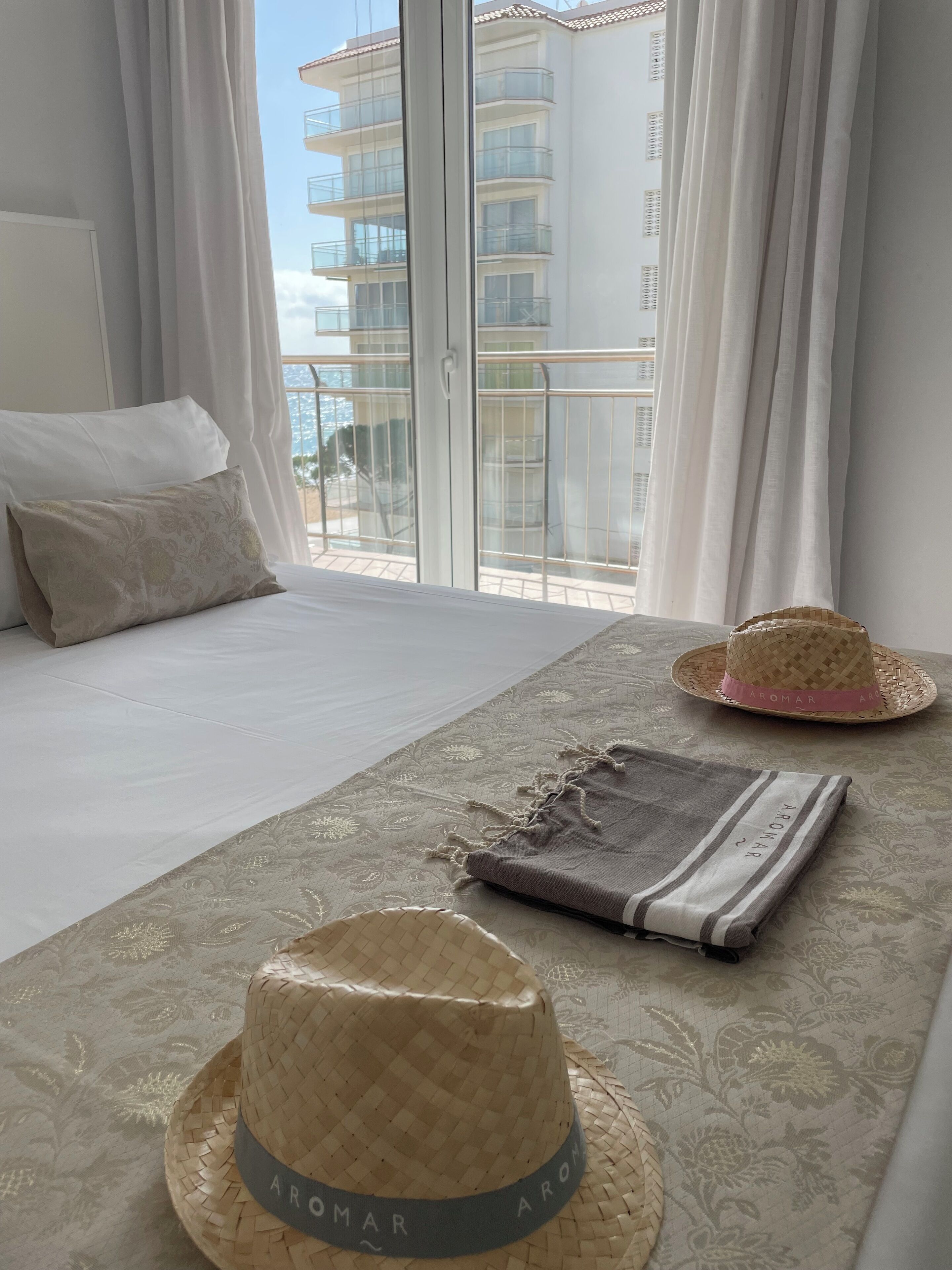 Ein Hotelzimmer mit Bett, Fenster mit Vorhängen und Blick auf ein Gebäude.