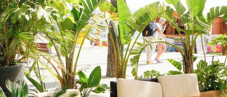 An outdoor seating area with a wicker sofa and potted plants.