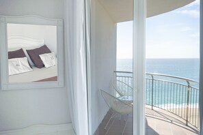A balcony with a view of the ocean, a white bed with pillows, and a chair. - Hotel Aromar (Castell-Platja d'Aro)