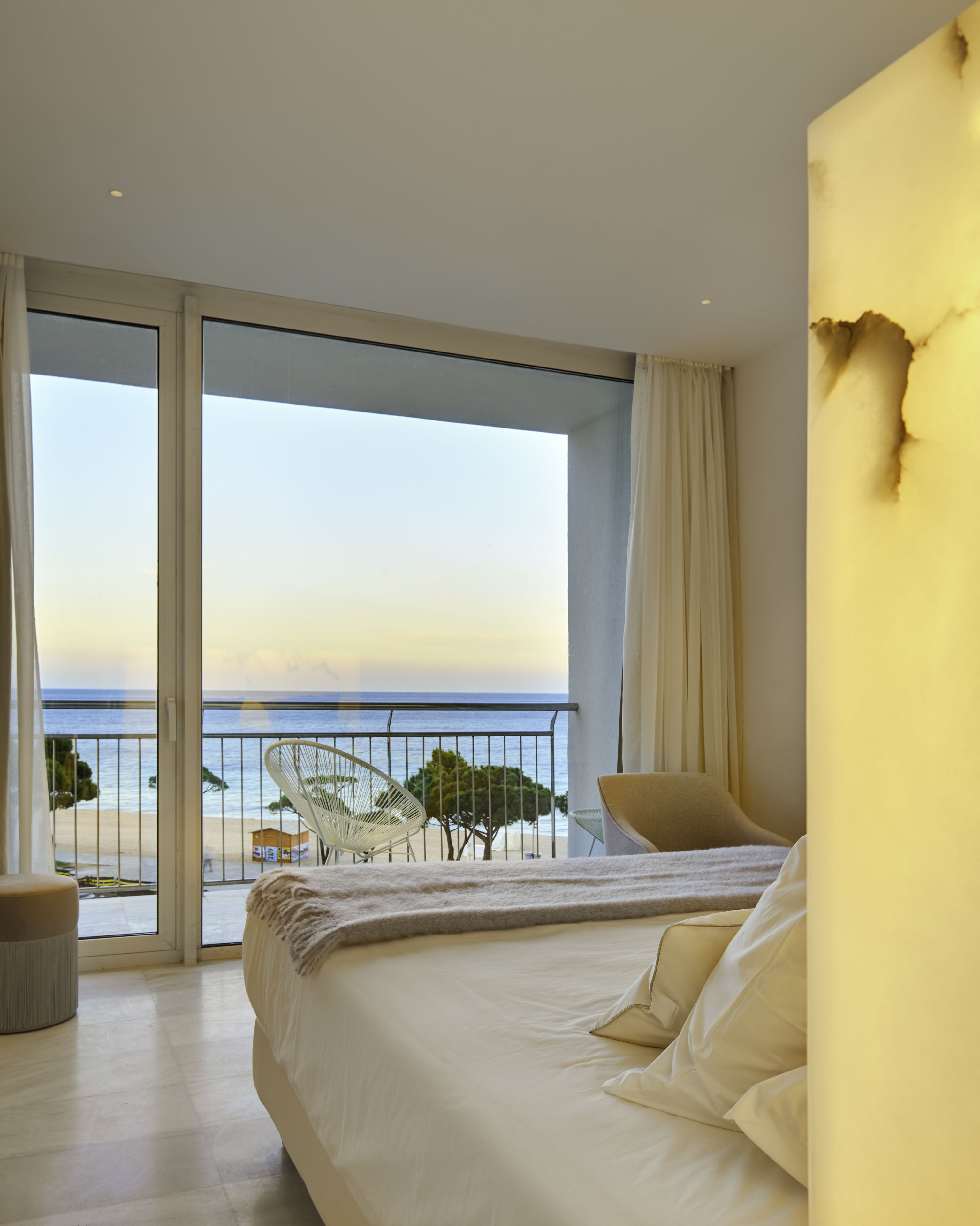 Una camera da letto con un letto grande, vista sul mare e un balcone con sedie.