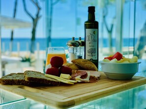 A wooden board with bread, cheese, ham, and a bottle of olive oil. - Hotel Aromar (Castell-Platja d'Aro)