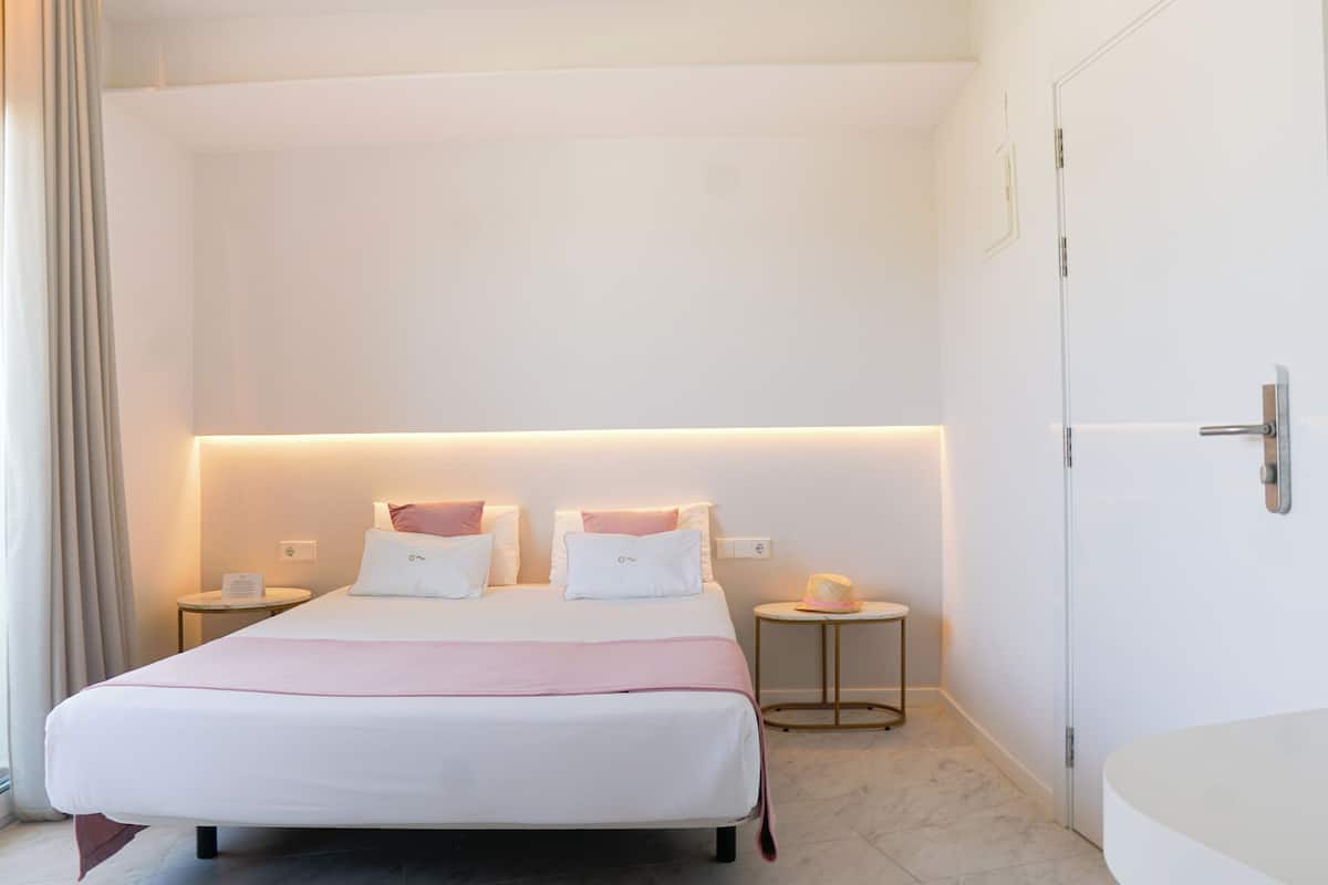 Ein Hotelzimmer mit einem großen Bett, Nachttischen und einer Tür.