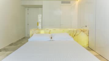 A bedroom with a bed, a marble headboard, a white door, and a white wardrobe.