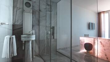 Un baño moderno con lavamanos de mármol, cabina de ducha de vidrio y tocador de mármol.