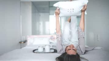 A person lying on a bed with a pillow labeled "ARO MAR" and a tray with two cups.