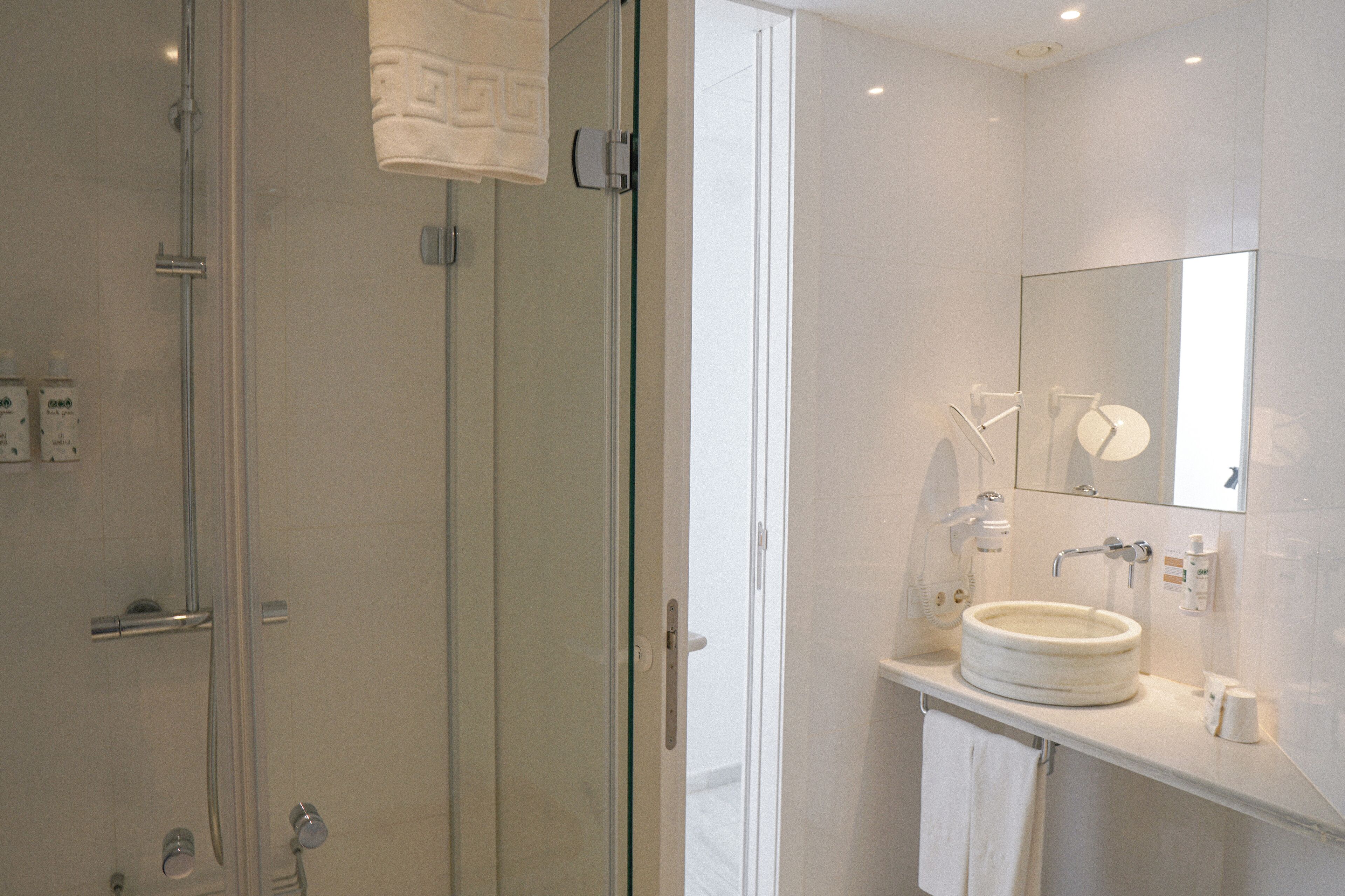 A modern bathroom with a glass shower enclosure, a round sink, and a mirror above the sink.