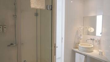 Un baño moderno con cabina de ducha de vidrio, un lavabo redondo y un espejo sobre el lavabo.
