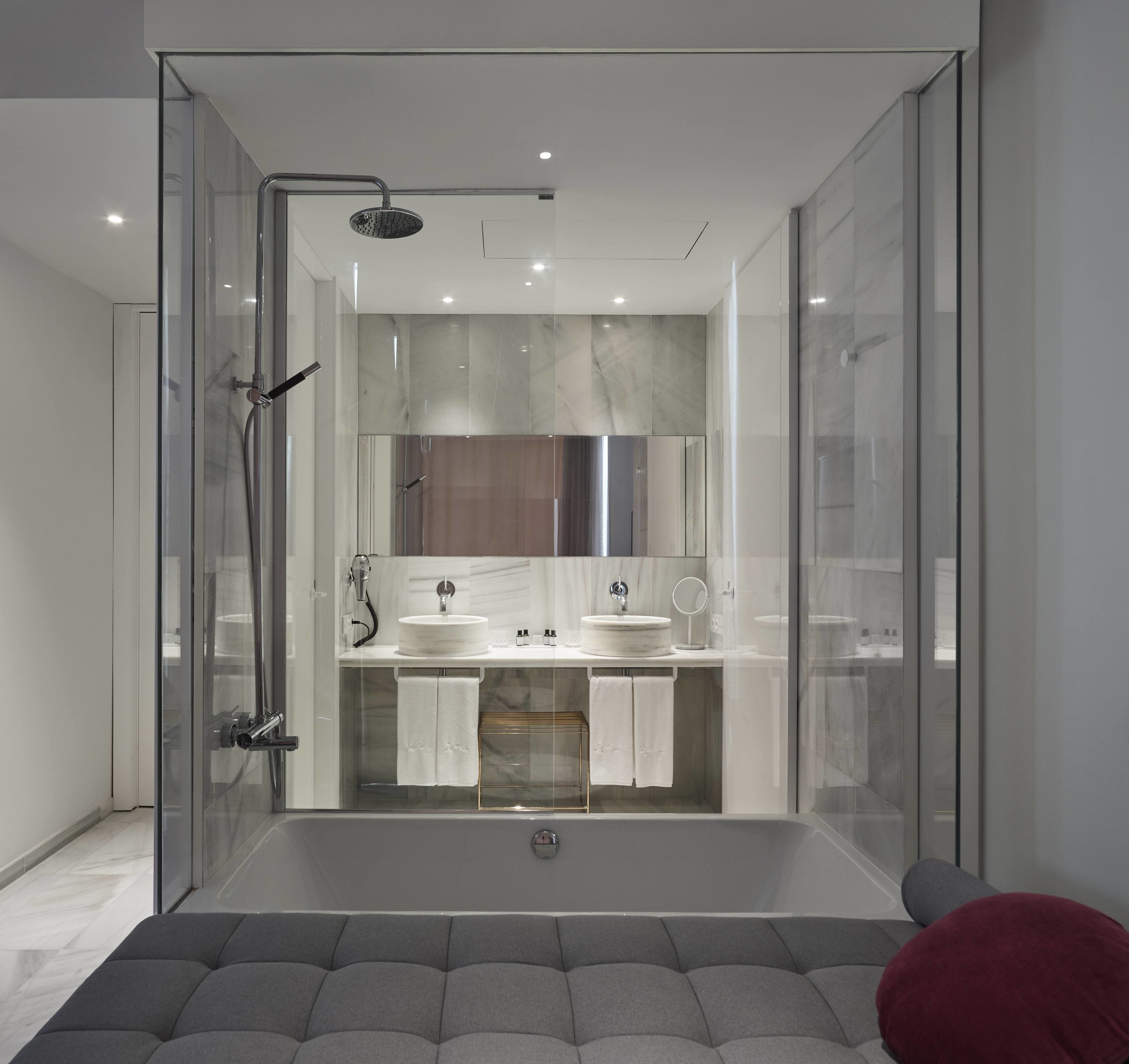 A modern bathroom with a glass-enclosed shower, two sinks, a large mirror, and a bathtub.