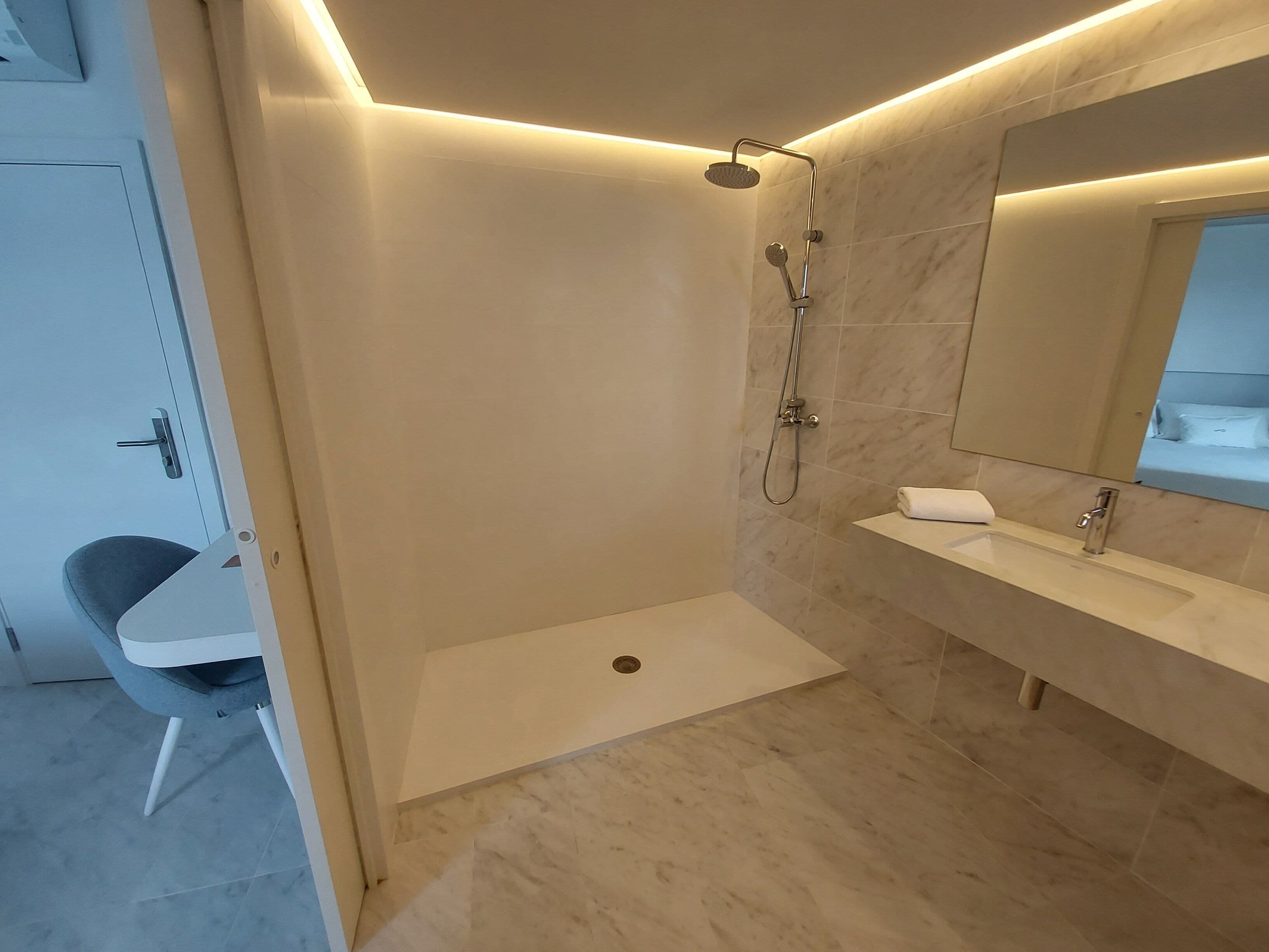 Un baño moderno con cabina de ducha, lavabo y espejo.