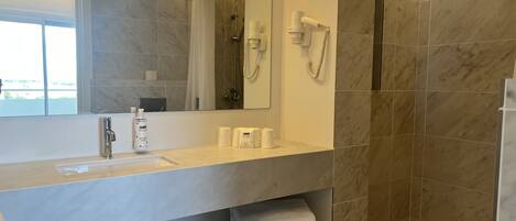 A modern bathroom with a large mirror, a sink, a shower, and a towel rack.