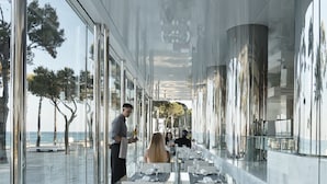 Un restaurante moderno con una amplia zona de comedor, grandes ventanales y vistas al mar.