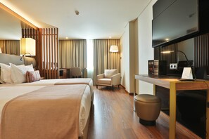 Une chambre d’hôtel avec deux lits, un bureau, une chaise, une télévision et une petite table avec une lampe.