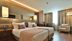 Ein Hotelzimmer mit zwei Betten, einem Schreibtisch, einem Stuhl und einem großen Spiegel.