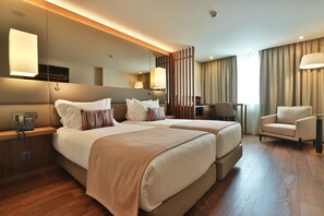 A hotel room with two beds, a desk, a chair, and a large mirror.