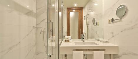 Un bagno moderno con cabina doccia in vetro, un lavandino bianco e una porta in legno.