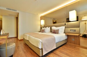 Habitación de hotel moderna con una cama grande, una mesita de noche, un escritorio y un espejo.