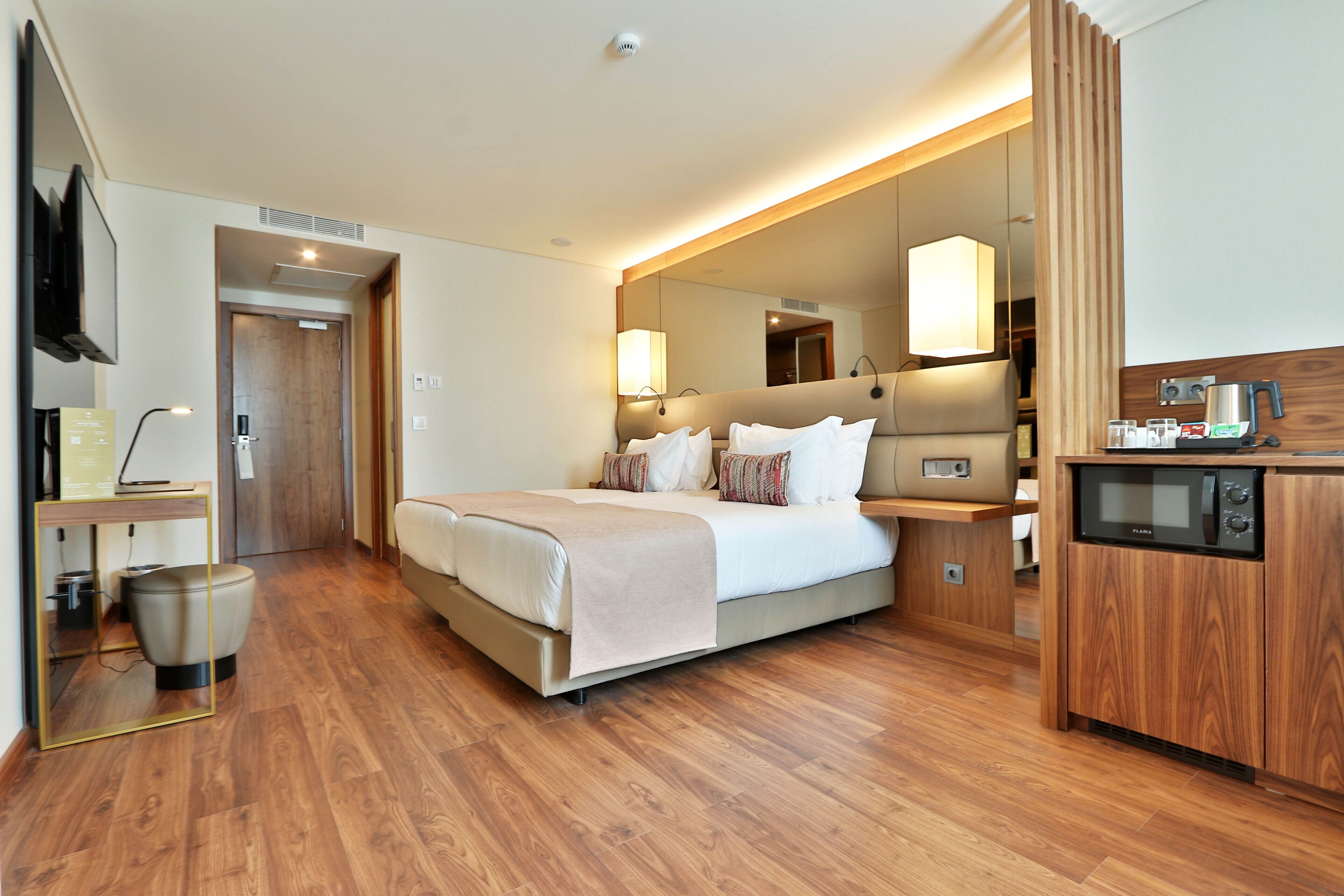 Een moderne hotelkamer met een groot bed, een nachtkastje, een televisie en een kitchenette.