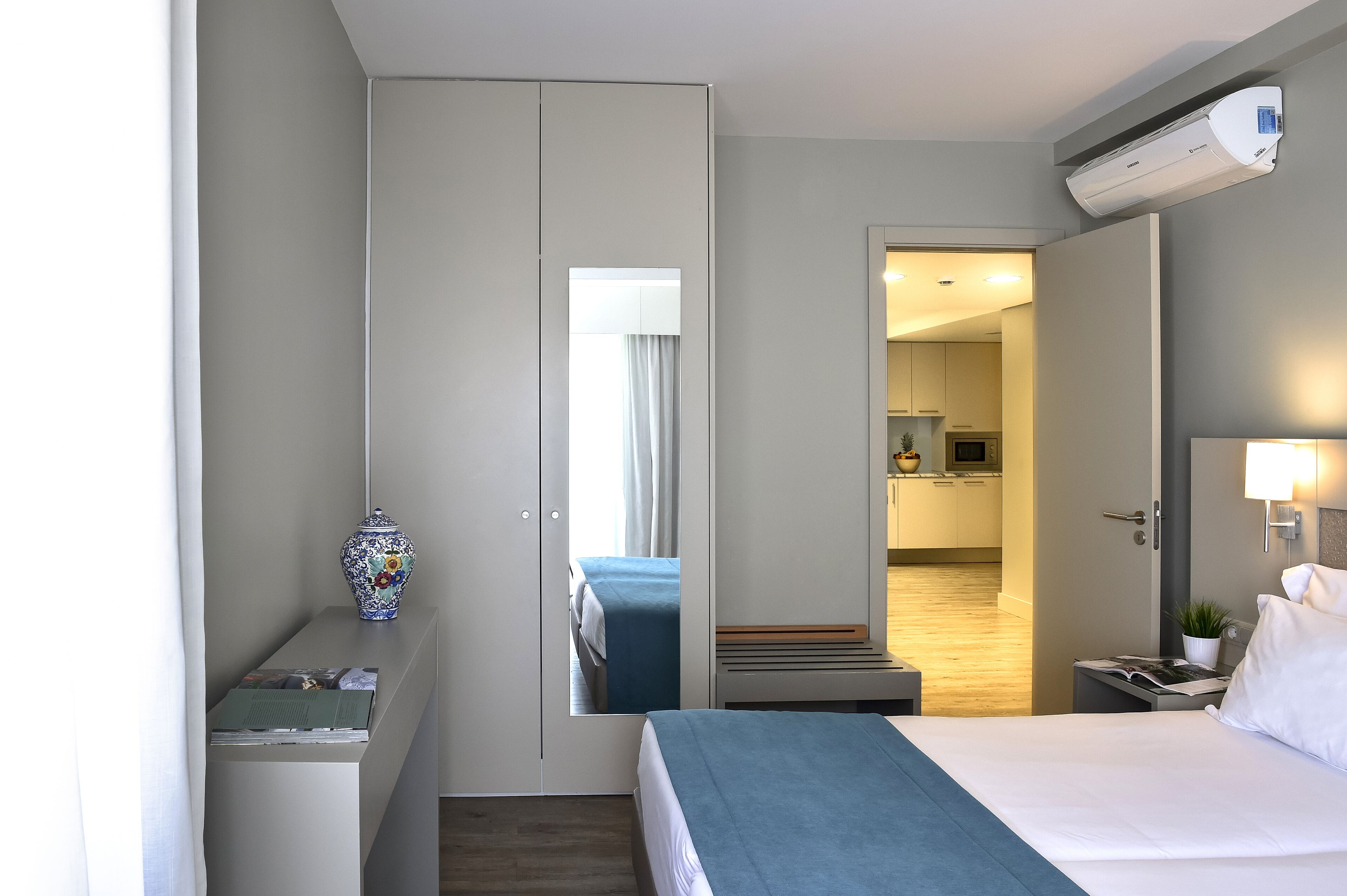 Une chambre d’hôtel comprenant un lit, une table de chevet, une lampe et donnant sur la cuisine.