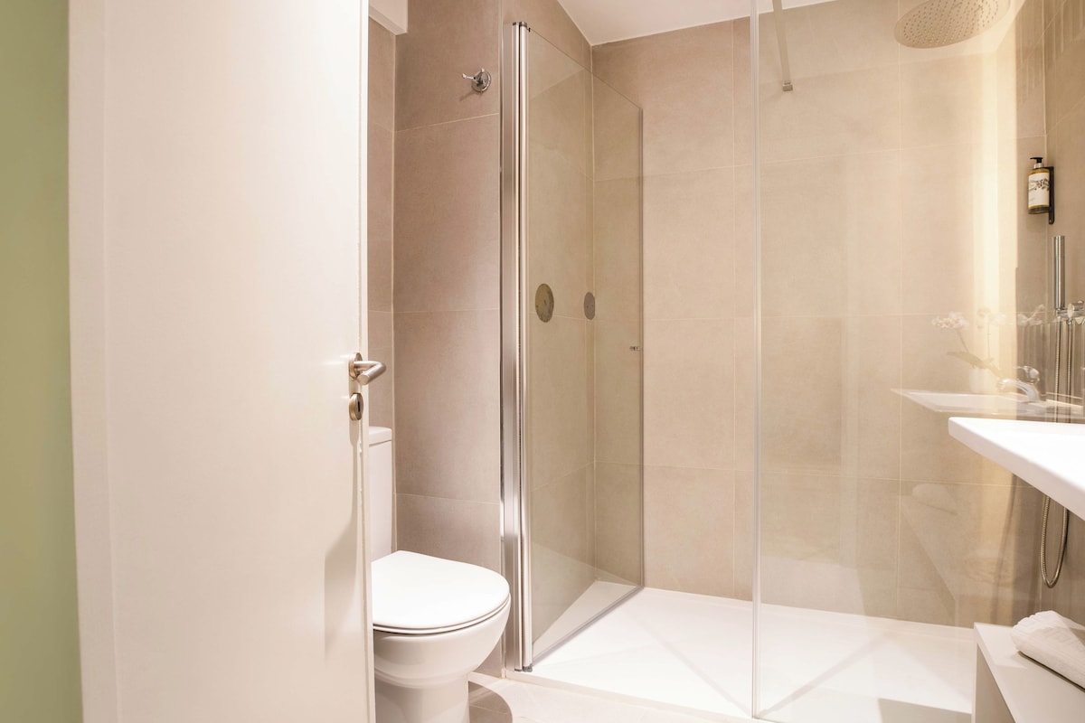 Un baño moderno con ducha de mampara, inodoro y lavamanos con espejo.