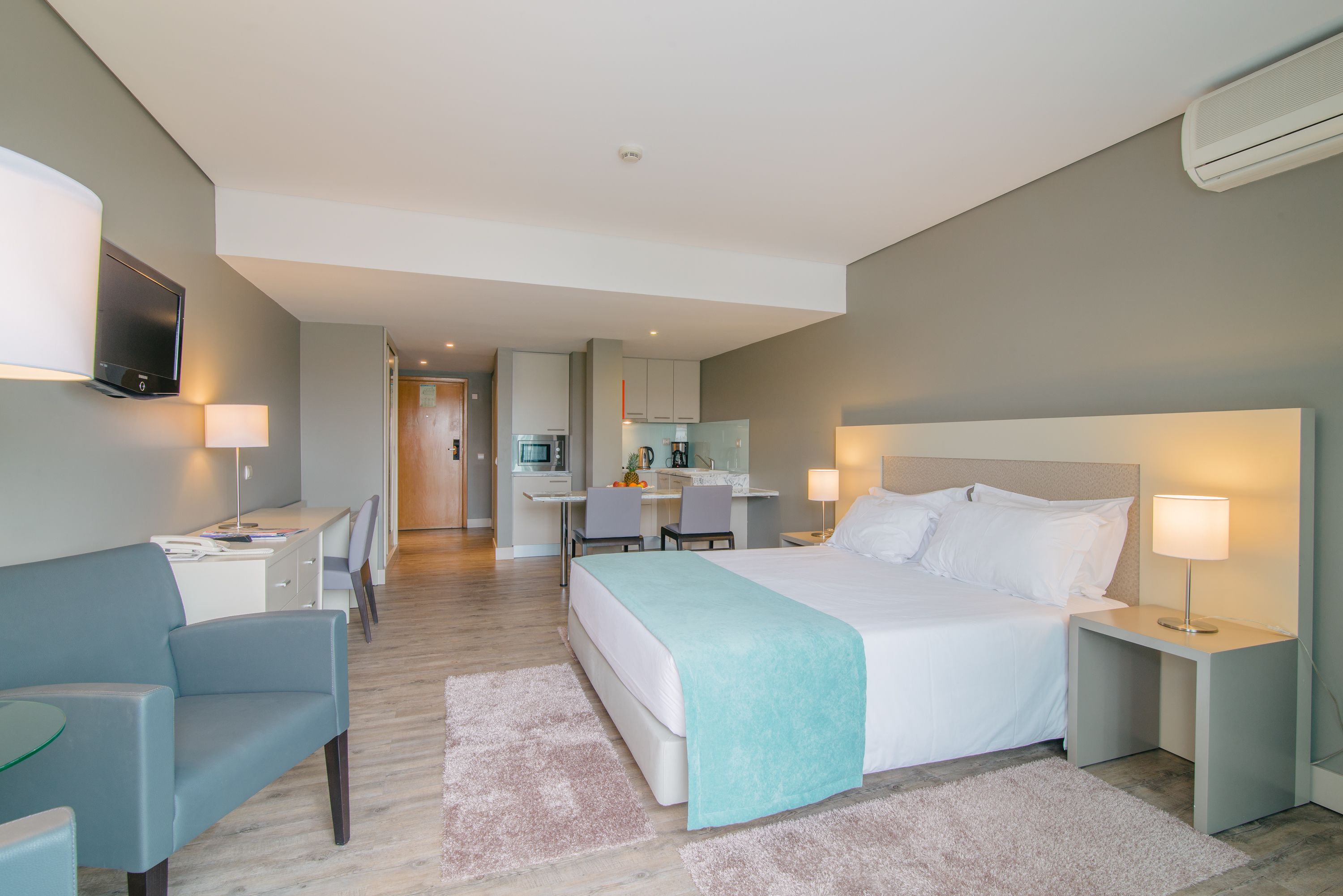 Ein modernes Hotelzimmer mit einem großen Bett, Nachttischen, einem Schreibtisch und einem Sessel.