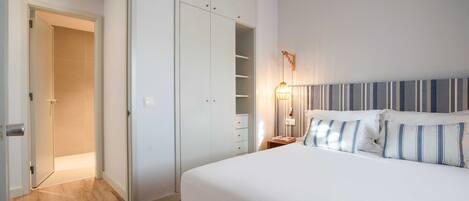 Una camera da letto con un letto, un armadio, un comodino e una lampada.
