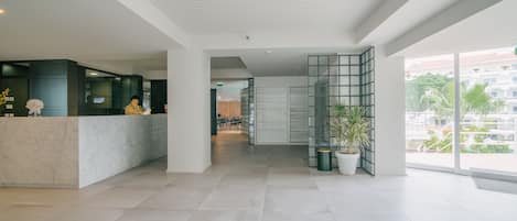 Um hall amplo com balcão de recepção, divisória de vidro e uma janela grande com vista para o exterior.
