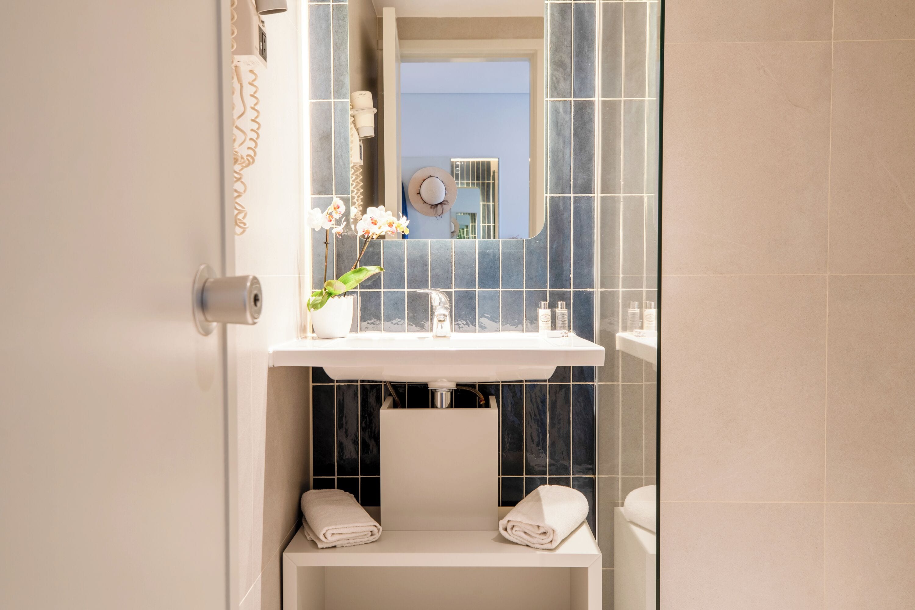 A bathroom with a white sink, a mirror, a towel rack, and a toilet.