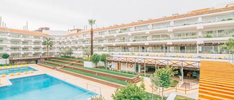 Un hôtel doté de nombreux balcons, d’une piscine et d’un espace extérieur aménagé et abrité.