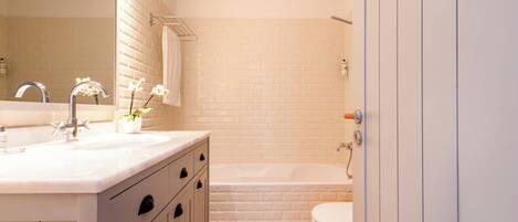 A bathroom with a white sink, mirror, and a bathtub.