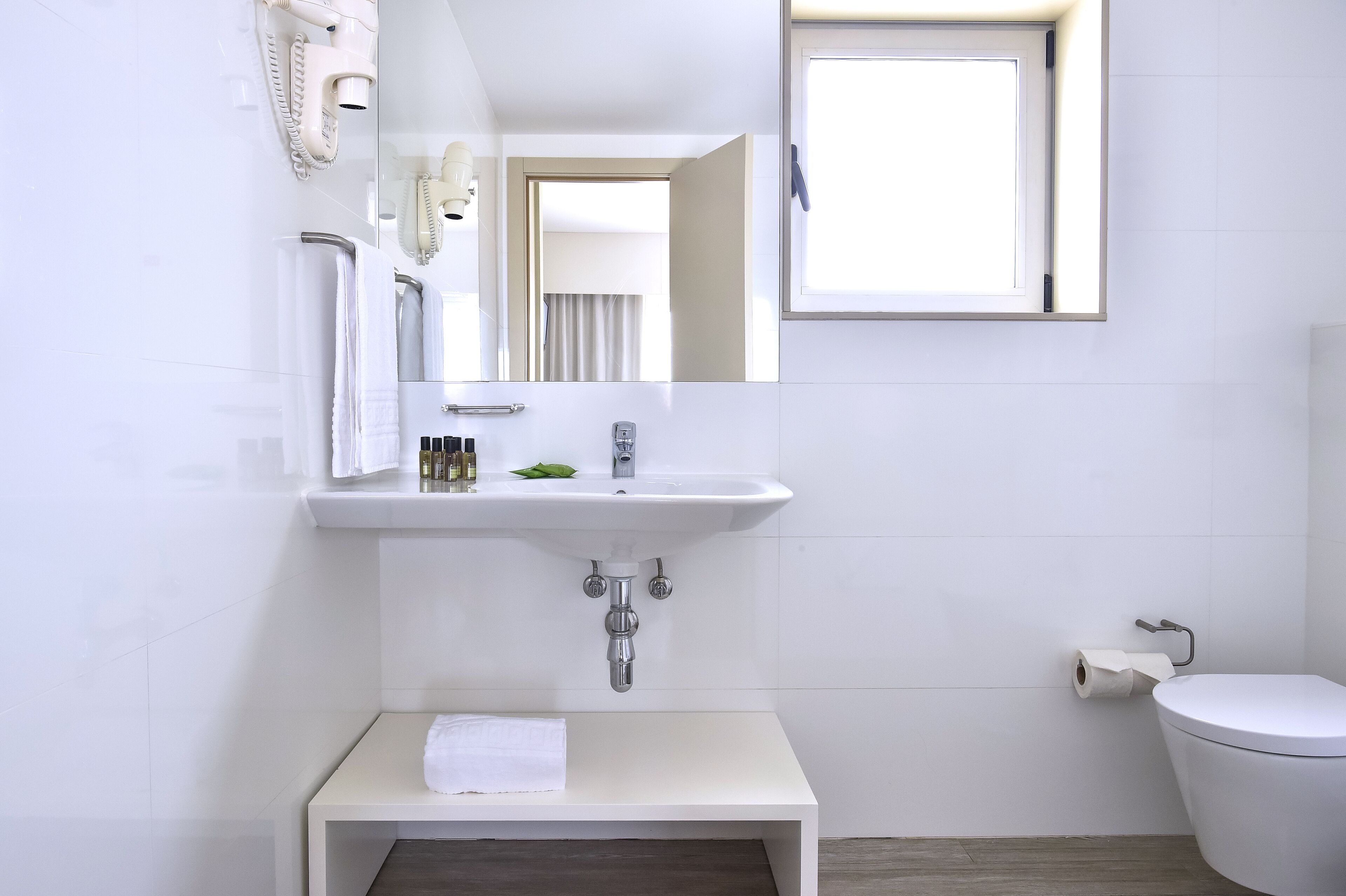 Et moderne badeværelse med hvid vask, spejl og toilet.