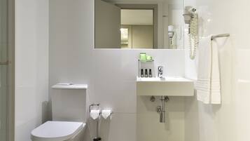Un baño moderno con inodoro, lavamanos y espejo.